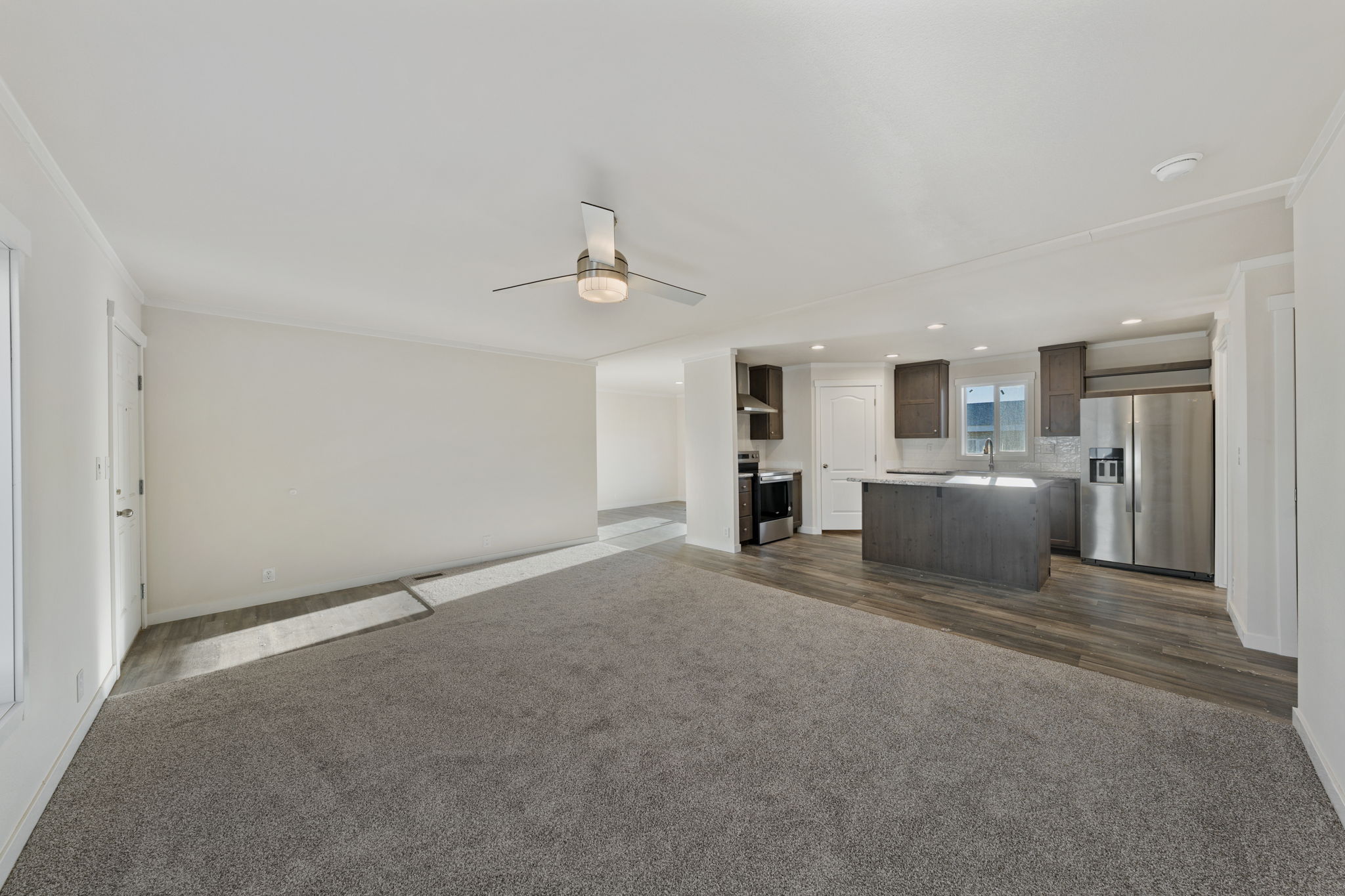 Living room view facing kitchen in Cavco Rhythm 28664R open concept home